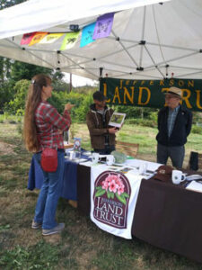 Table with Land Trust gear and three people chatting