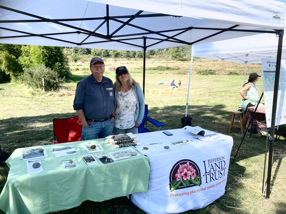 Two people smiling under tent and behind info table