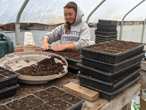 Woman putting dirt into pots in greenhouse