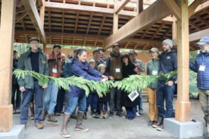 Happy group and woman cutting cedar bough ribbon